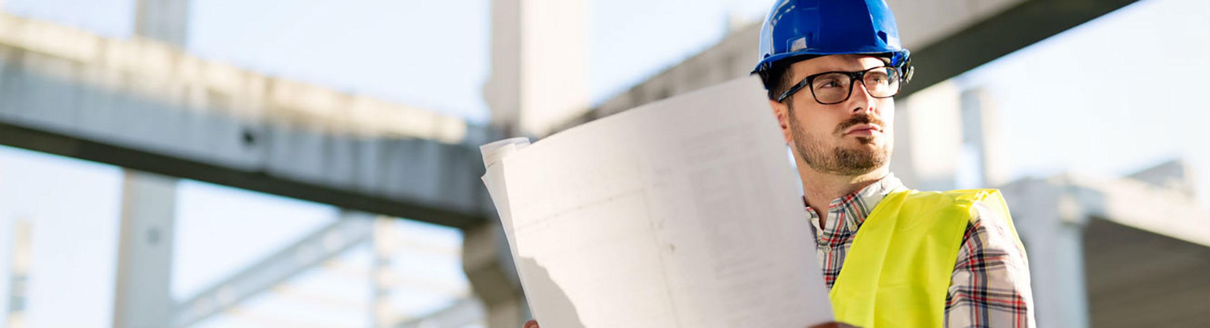 Homme lit un plan et travaille dans le secteur du bâtiment